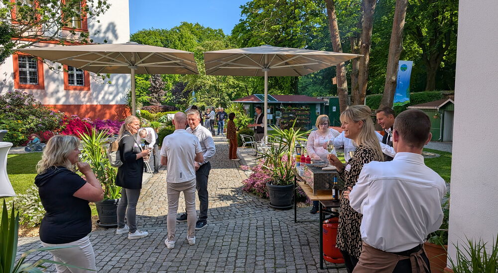 Im Klostergarten stehen viele Menschen und unterhalten sich.