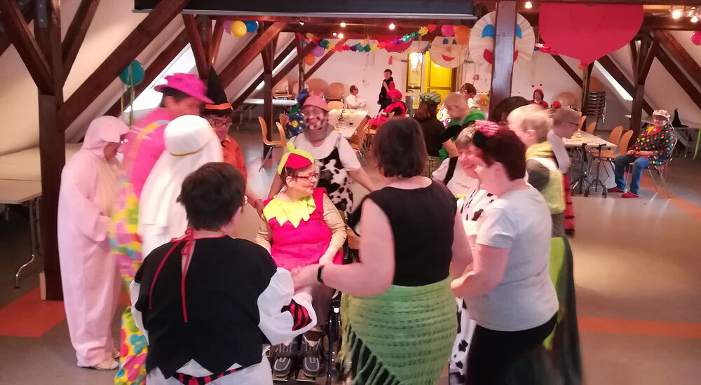 Klienten feiern mit den Betreuer Fasching und singen und tanzen mit Kostümen.
