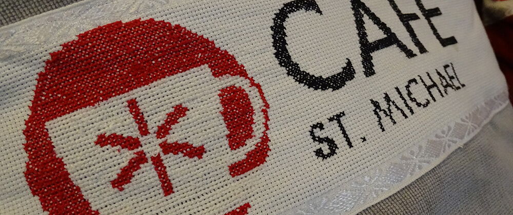 Logo des Café auf ein Kissen gestickt.