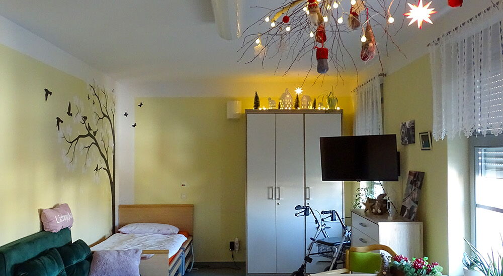 Hier ist ein geschmücktes Zimmer der Wohngemeinschaft mit Bett und Schrank zu sehen.