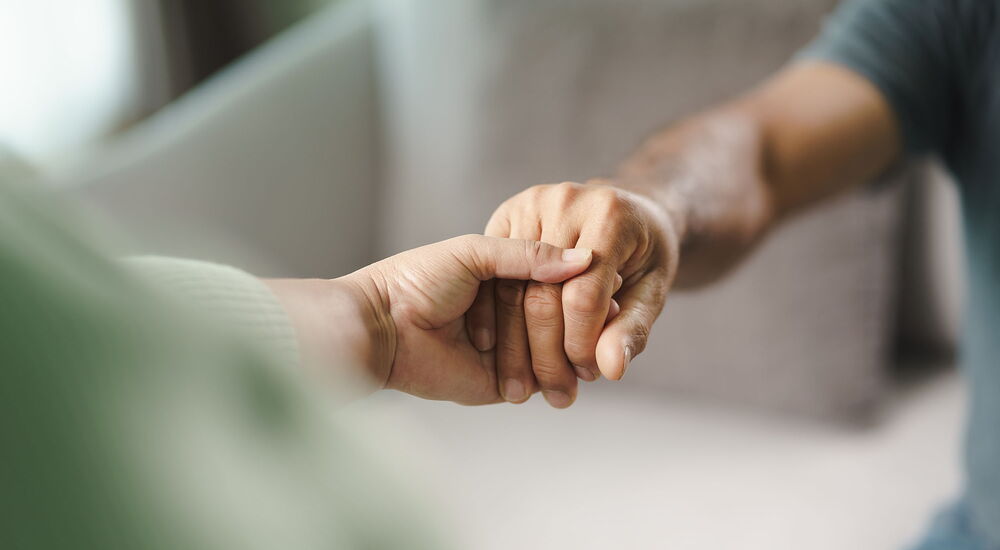 Ein Pfleger oder Betreuer nimmt eine weitere Person an die Hand.