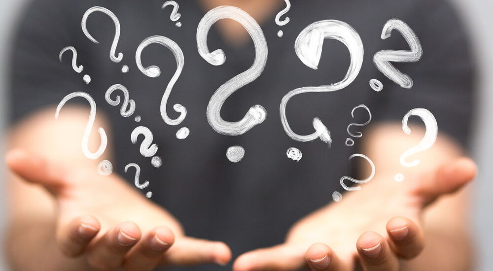Zwei nach vorn geöffnete Hände in der viele Fragezeichen hochkommen